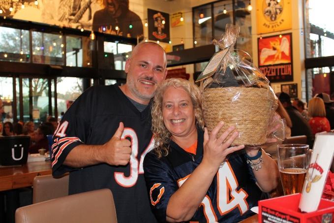 Two Kick Off for Kids supporters in football jerseys holding a raffle basket.